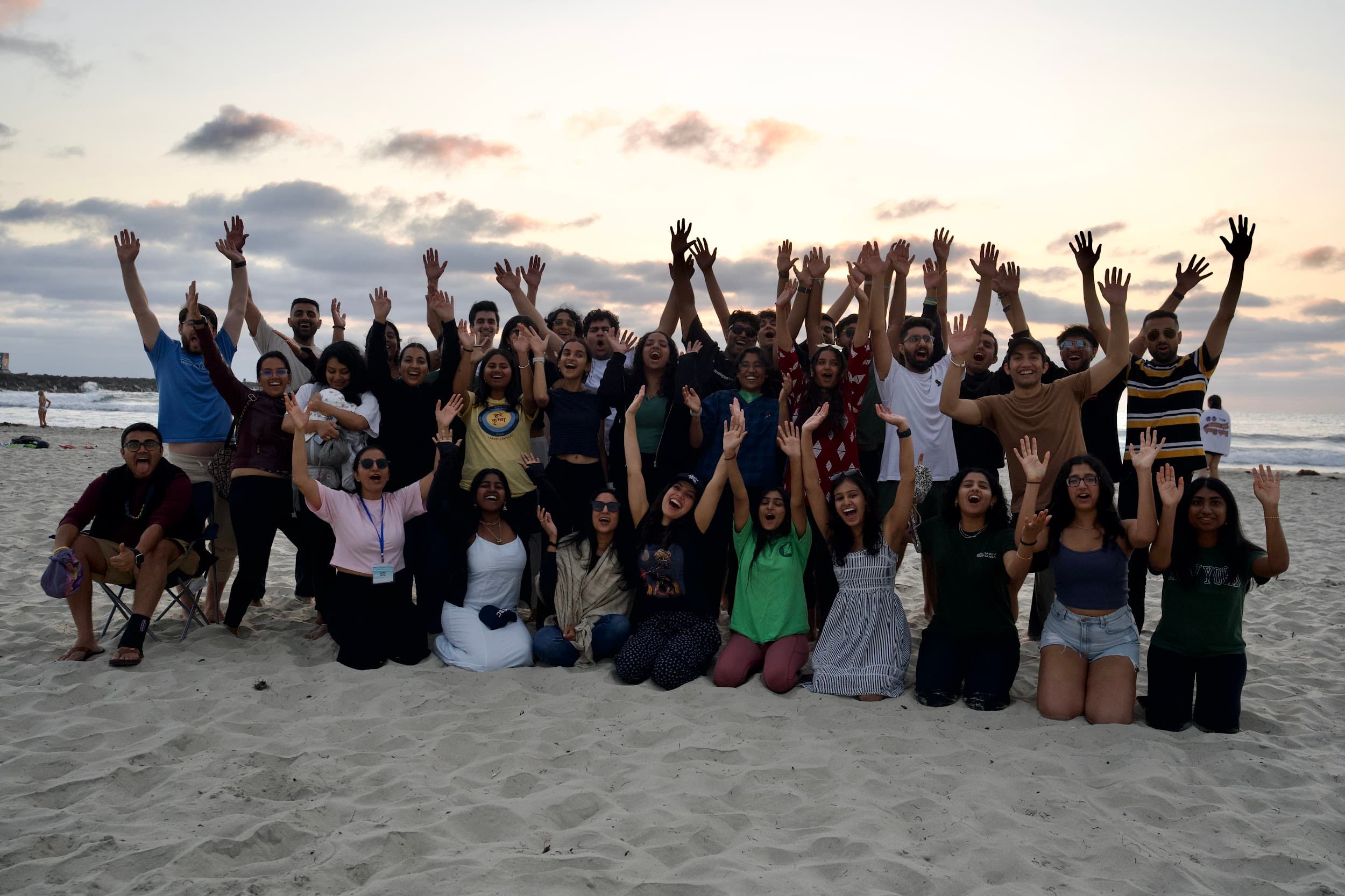 A full retreat group standing together on the beach at sunset